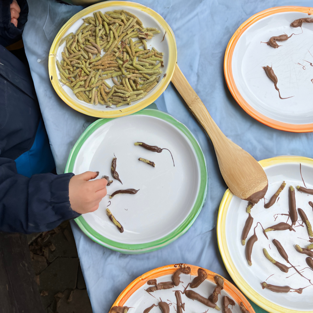 Kinder tauchen Haselkätzchen in Schokolade und legen sie auf einen Teller