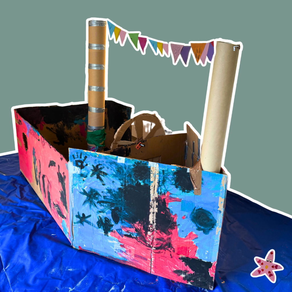 Großes selbstgebautes Schiff aus Pappkartons, welches bunt angemalt ist.