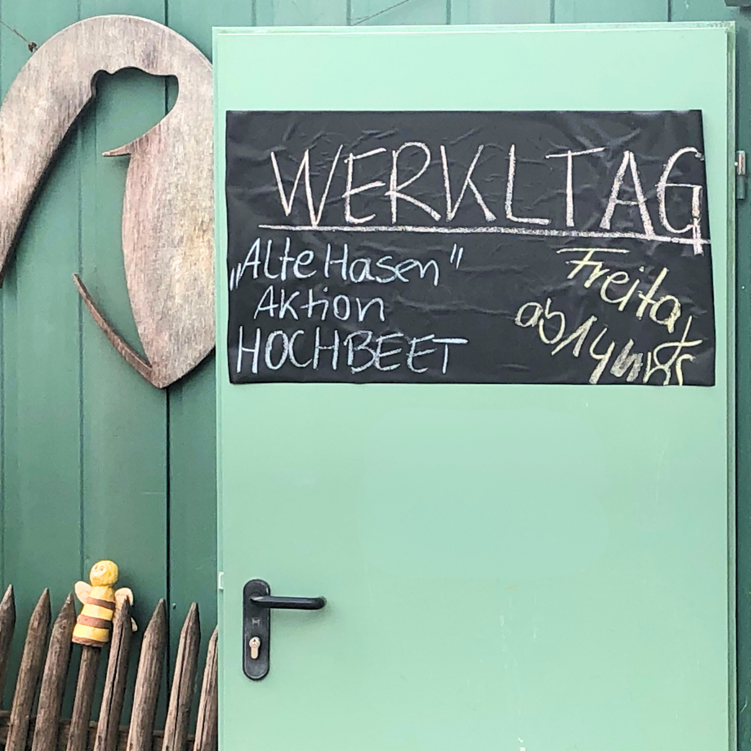 Eine Tafel an einer Tür auf der der anstehende Werktag der Eltern im Waldkindergarten Pielenhofen angekündigt wird.