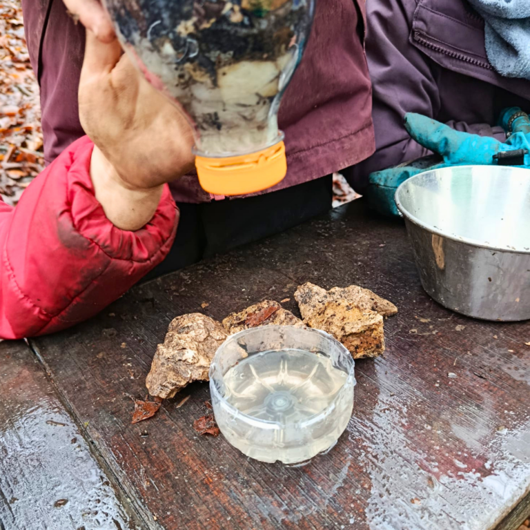 Kinderhände, die Wasser durch eine Flasche filtern