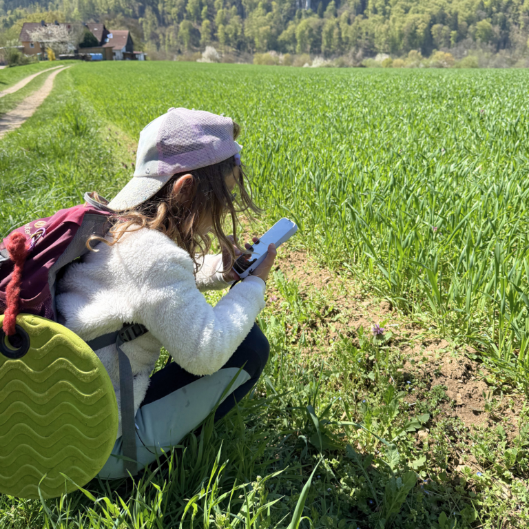 Ein Mädchen, dass mit einem Handy eine Blume filmt.