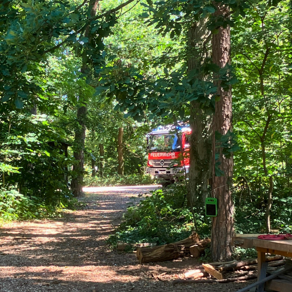 Ein Feuerwehrauto, dass durch den Wald fährt.