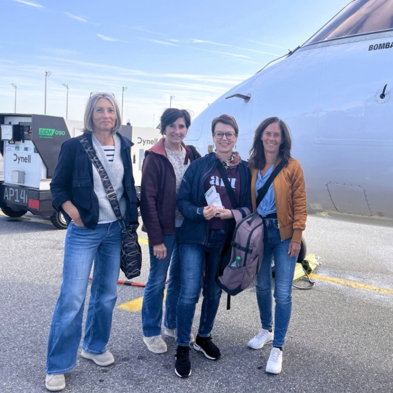 Vier Frauen, die vor einem Flugzeug stehen.
