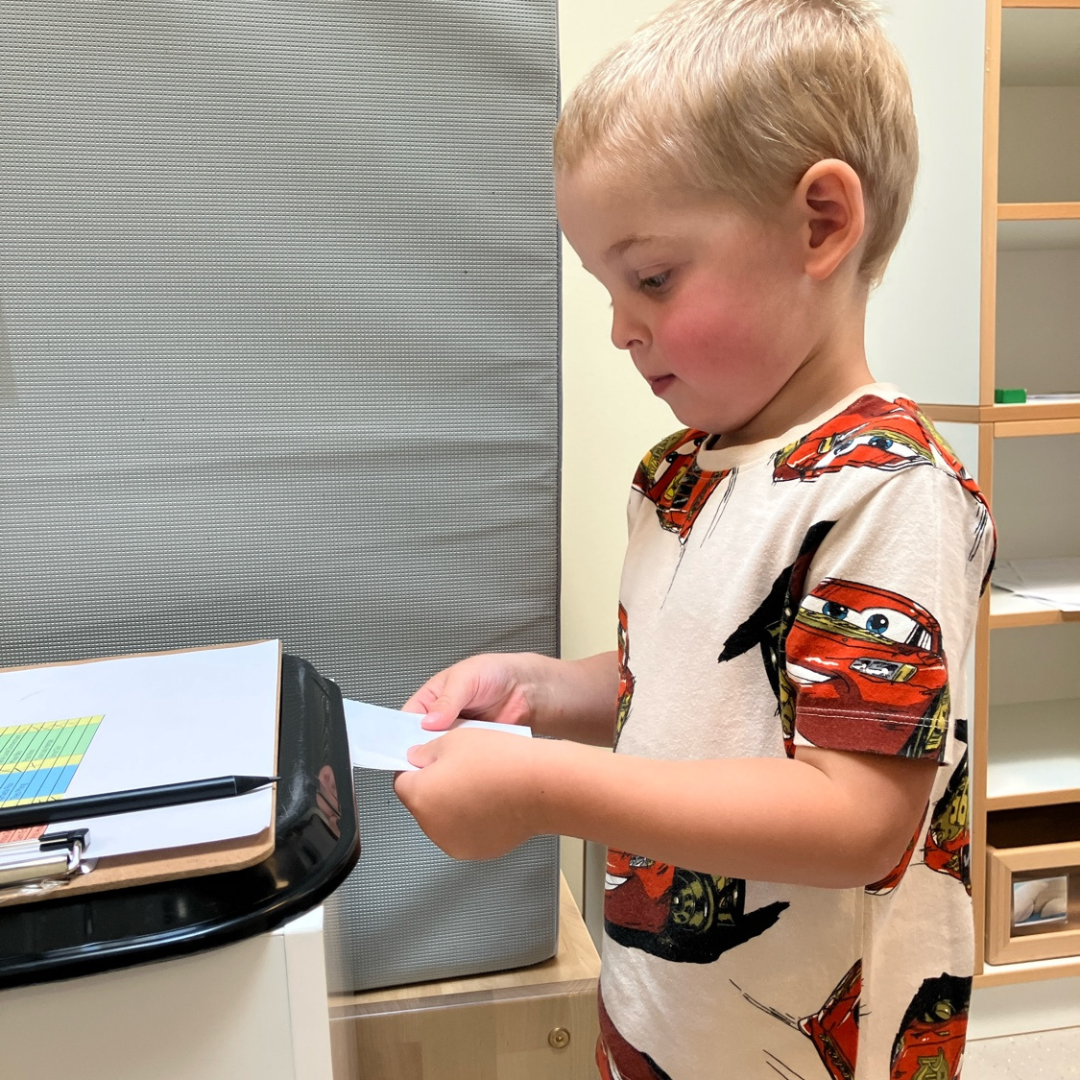 Ein Kind wirft seinen Stimmzettel der Kinderparlaments-Wahl in die Wahlurne.