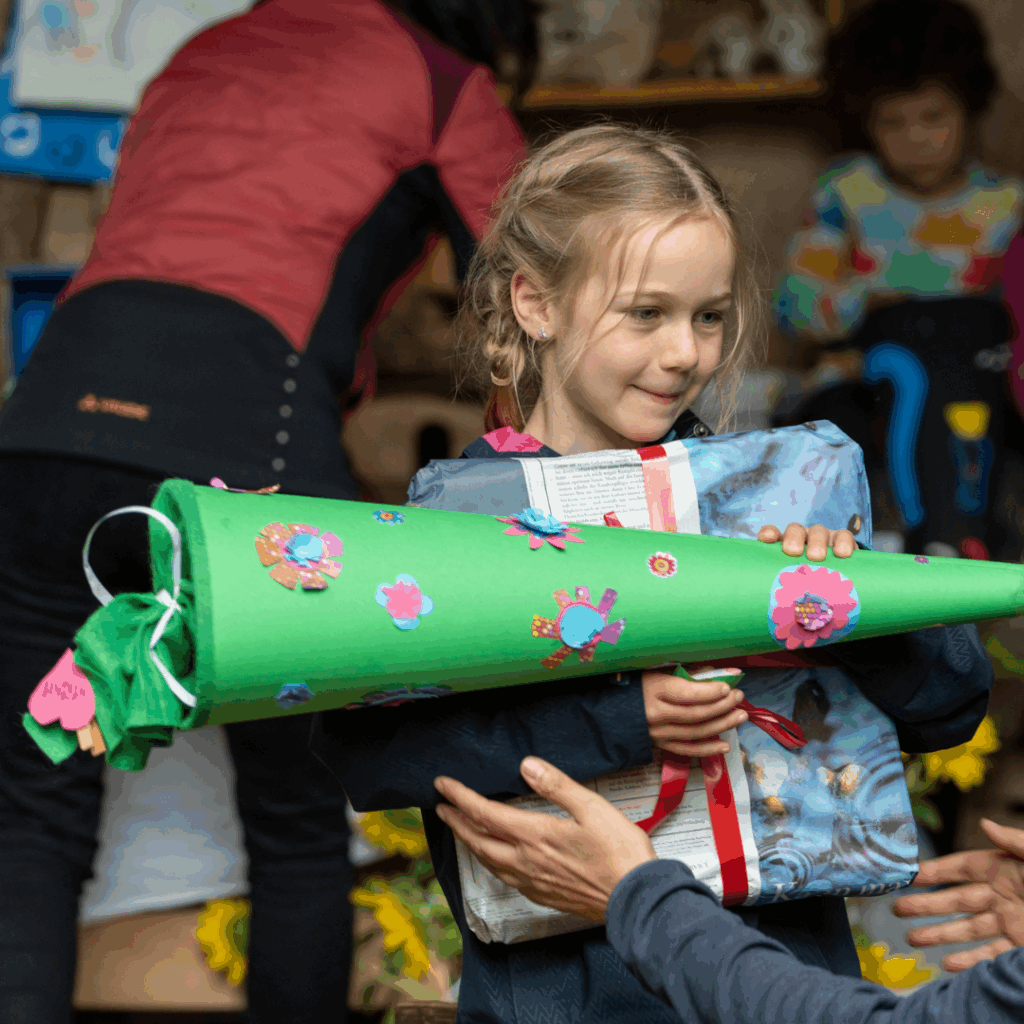 Ein Mädchen mit einer Schultüte und einem Geschenk in den Armen