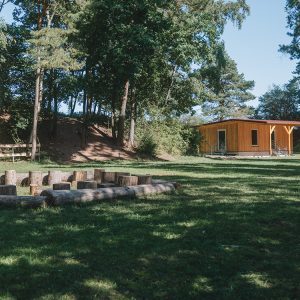 Gelände der Waldkinder Herrieden mit einem Sitzkreis aus Baumstämmen und einer Schutzhütte